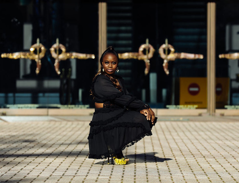 Woman in a black dress sitting on a stone pavement in front of the Gus S. Wortham Theater Center.