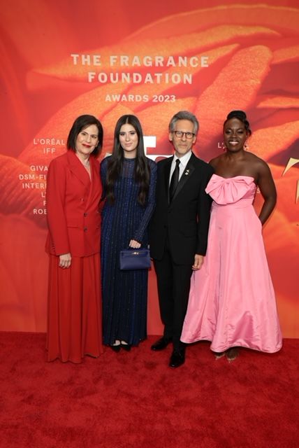 Four people posing on a red carpet at the Fragrance Foundation Awards 2023 with an orange backdrop.