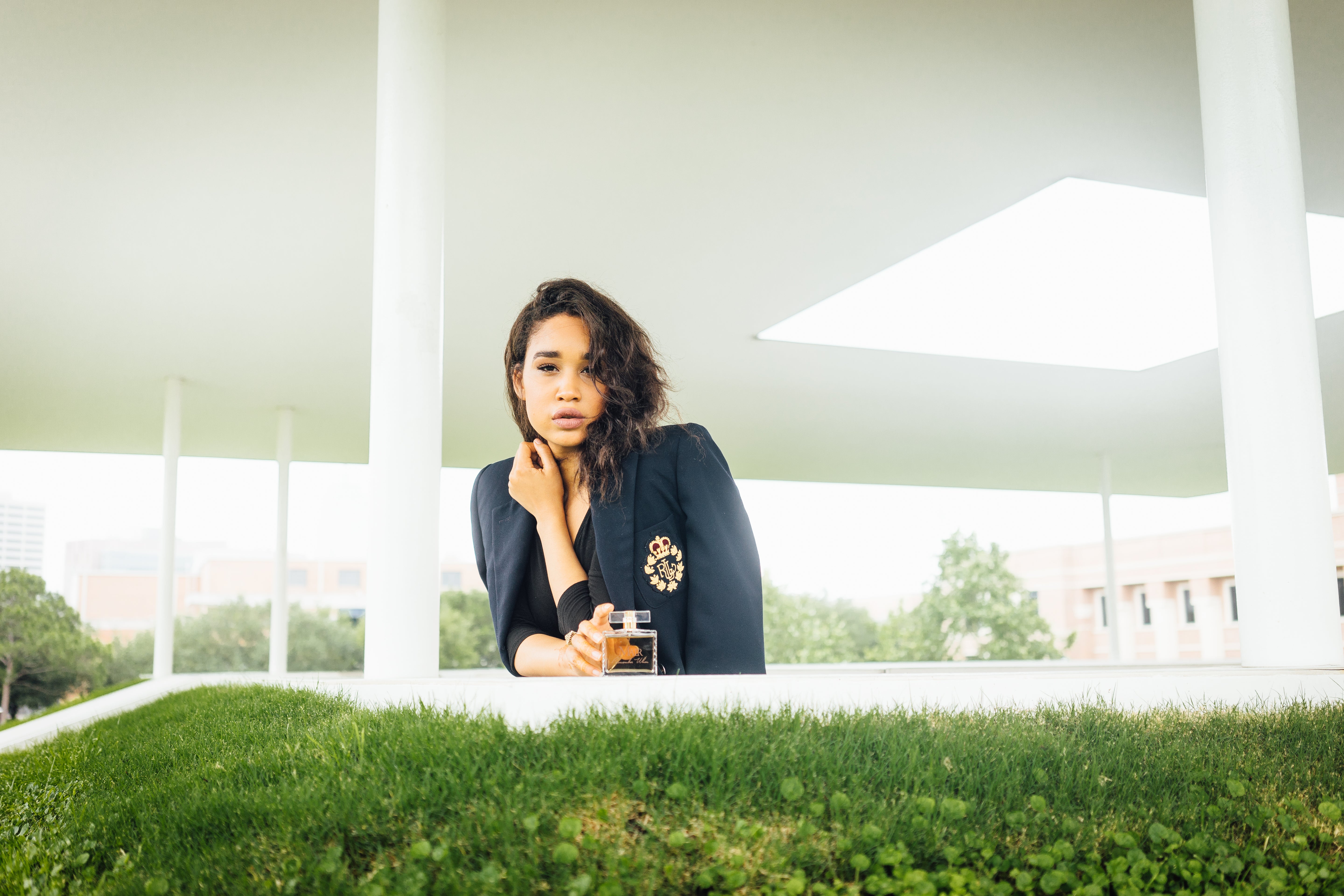Woman sitting on grass under a modern architectural structure